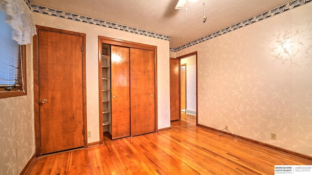 unfurnished bedroom with ceiling fan, light hardwood / wood-style floors, and a closet