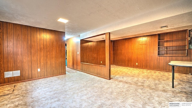 basement with light colored carpet, a textured ceiling, and wooden walls