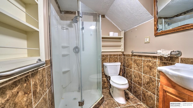 bathroom with vanity, a shower with door, tile walls, and a textured ceiling