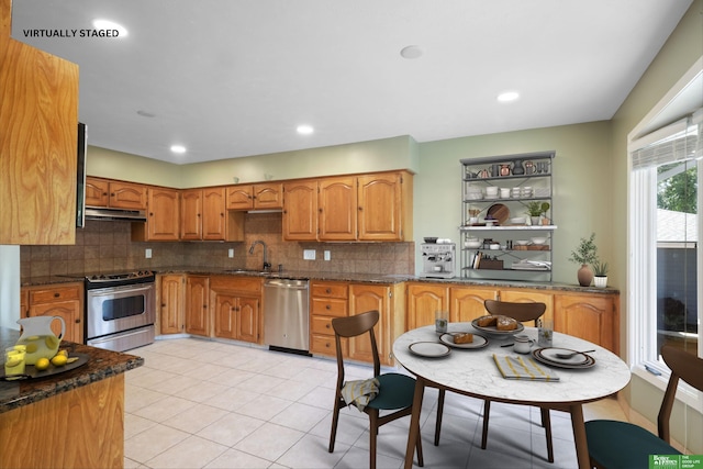 kitchen featuring sink, appliances with stainless steel finishes, tasteful backsplash, light tile patterned flooring, and dark stone counters