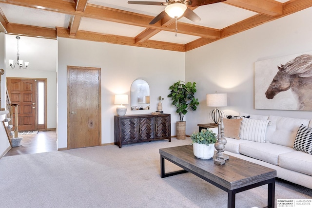 living room with coffered ceiling, ceiling fan with notable chandelier, light colored carpet, and beamed ceiling