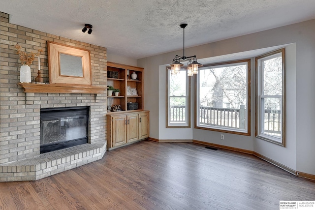 unfurnished living room featuring a brick fireplace, hardwood / wood-style flooring, and a textured ceiling