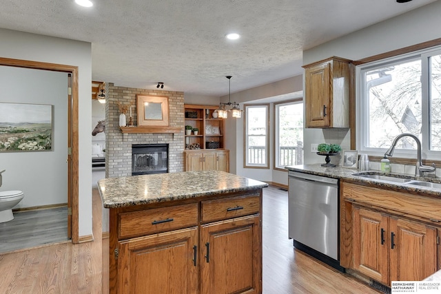 kitchen with sink, light hardwood / wood-style flooring, dishwasher, a kitchen island, and pendant lighting