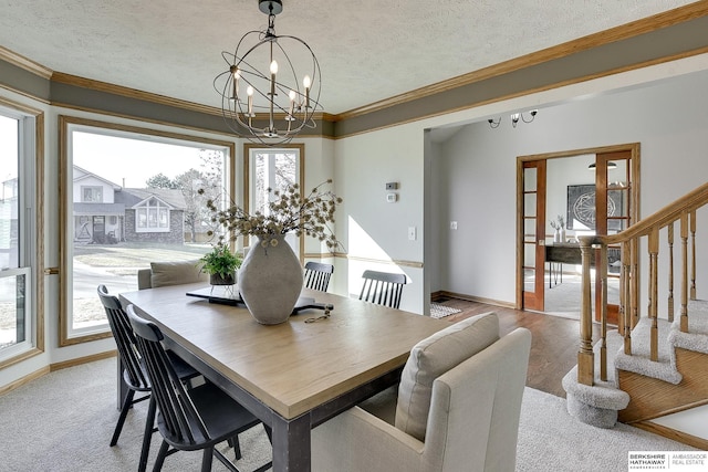 dining area featuring a notable chandelier, ornamental molding, french doors, and a textured ceiling