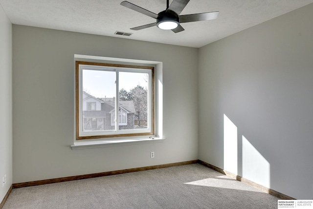 carpeted spare room featuring ceiling fan and a textured ceiling