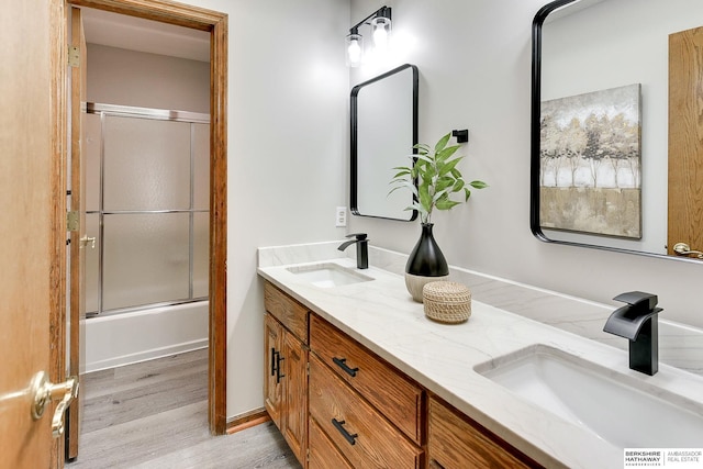 bathroom featuring hardwood / wood-style flooring, bath / shower combo with glass door, and vanity