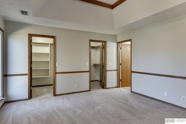 unfurnished bedroom featuring light carpet, a spacious closet, a closet, and a raised ceiling