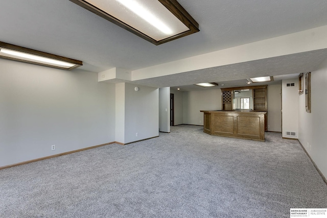 interior space with light colored carpet, a textured ceiling, and indoor bar