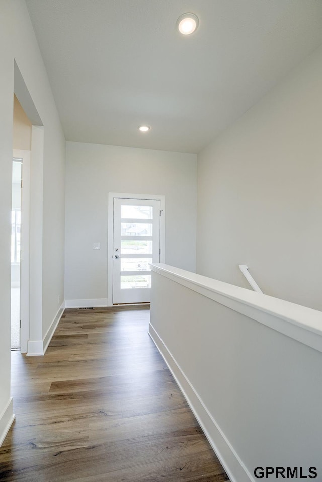 corridor featuring light wood-type flooring, baseboards, and recessed lighting