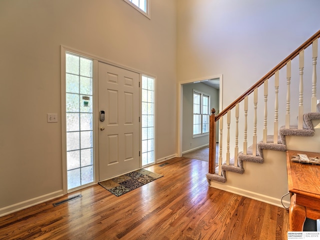 foyer entrance featuring hardwood / wood-style floors and a high ceiling