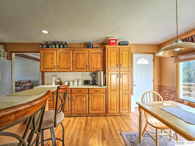 kitchen featuring tasteful backsplash, pendant lighting, stainless steel refrigerator, and light hardwood / wood-style flooring