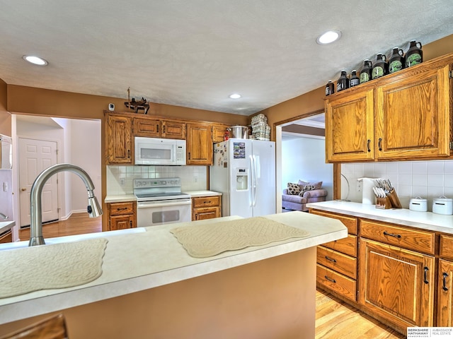 kitchen with tasteful backsplash, sink, white appliances, and light wood-type flooring