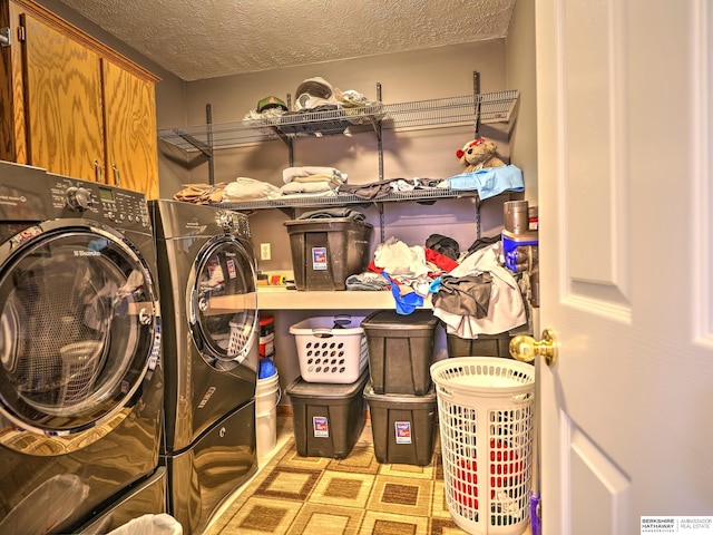 washroom featuring cabinets, washing machine and clothes dryer, and a textured ceiling