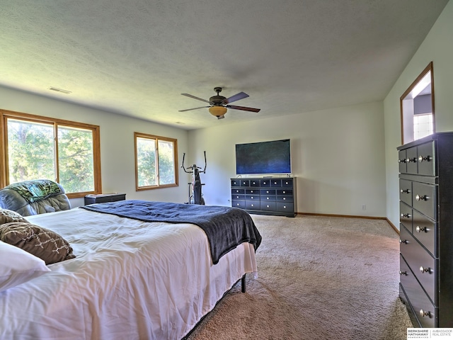 carpeted bedroom featuring ceiling fan and a textured ceiling