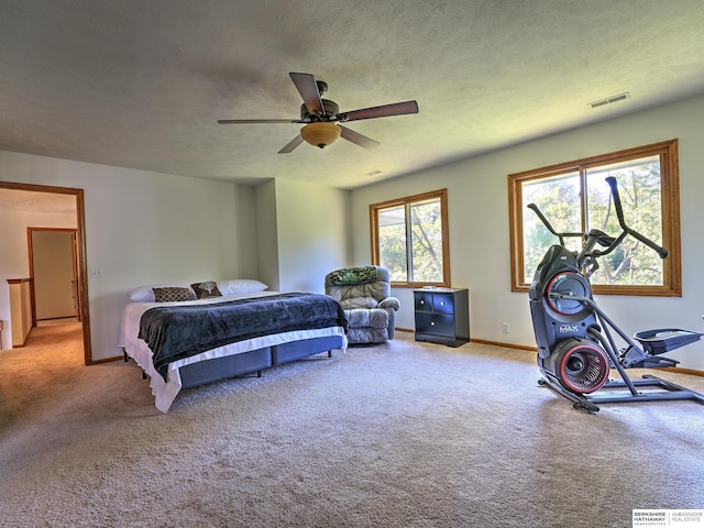 bedroom with ceiling fan, light carpet, and a textured ceiling