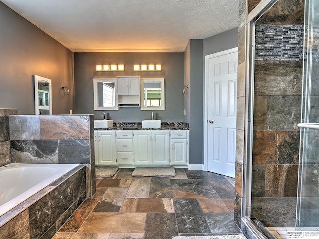 bathroom with vanity, independent shower and bath, and a textured ceiling