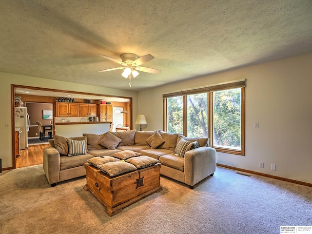 carpeted living room featuring ceiling fan and a textured ceiling