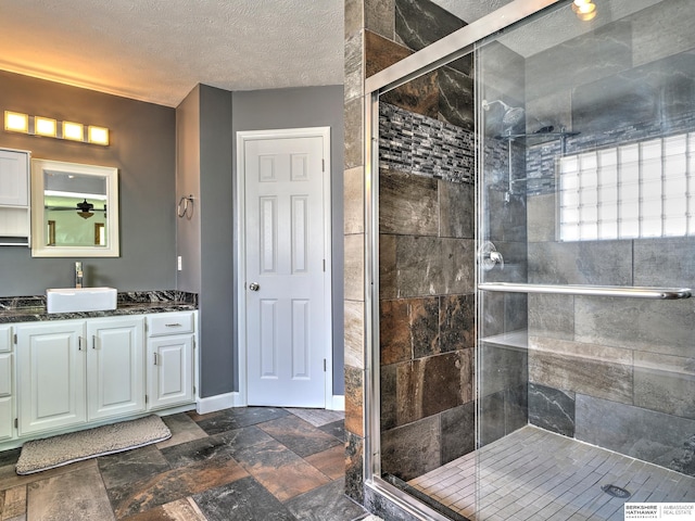 bathroom featuring walk in shower, vanity, and a textured ceiling