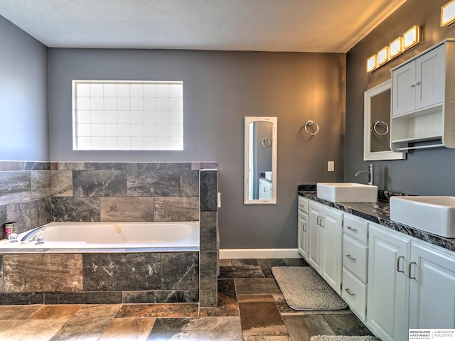 bathroom featuring a relaxing tiled tub and vanity