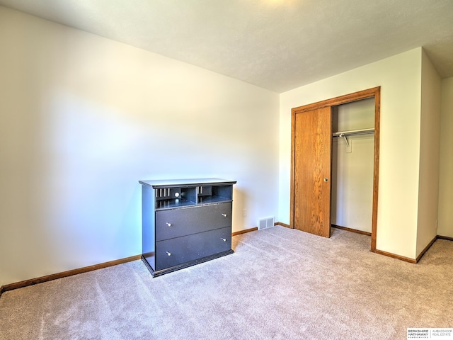 unfurnished bedroom featuring light carpet and a closet