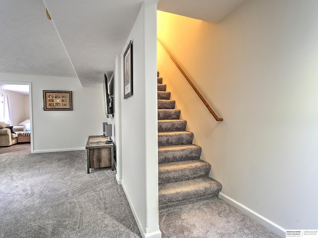 stairs featuring carpet and a textured ceiling