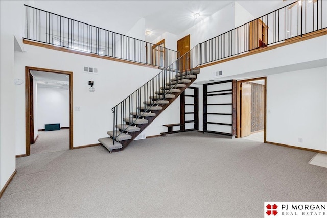 stairs featuring a high ceiling and carpet flooring