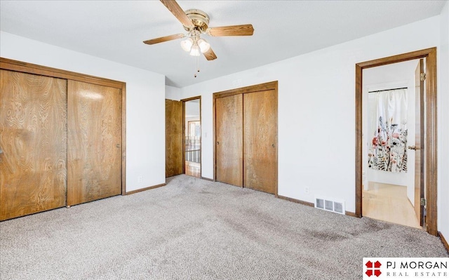 unfurnished bedroom with multiple closets, ceiling fan, and light carpet