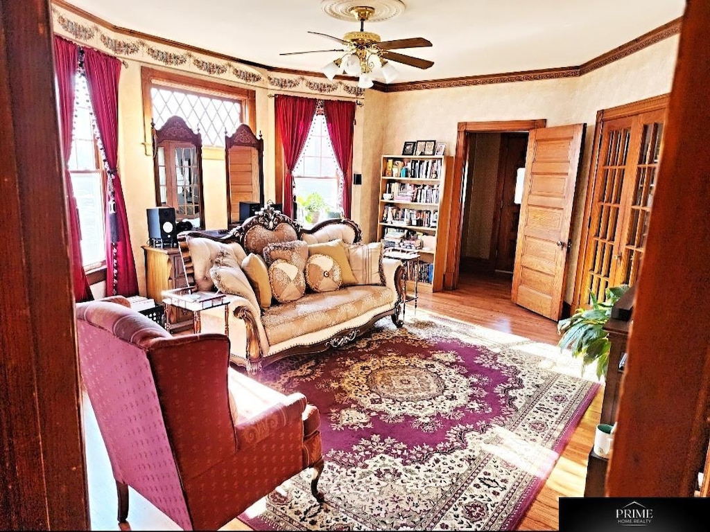 living room with ceiling fan, ornamental molding, and light wood-type flooring