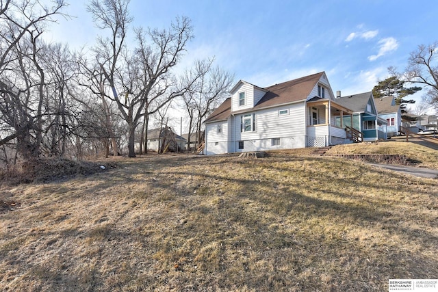 view of side of home featuring a porch and a yard