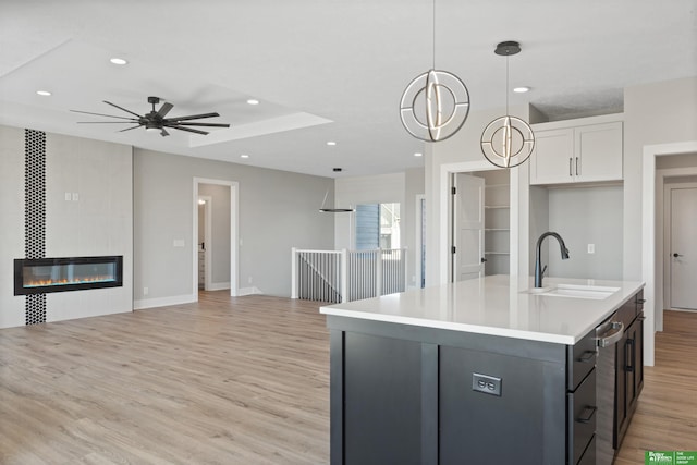 kitchen featuring light wood-style floors, open floor plan, a fireplace, and a sink