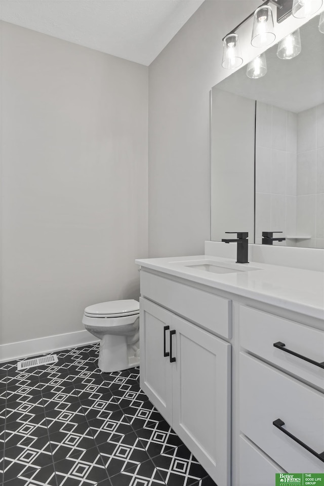 bathroom with toilet, baseboards, and vanity