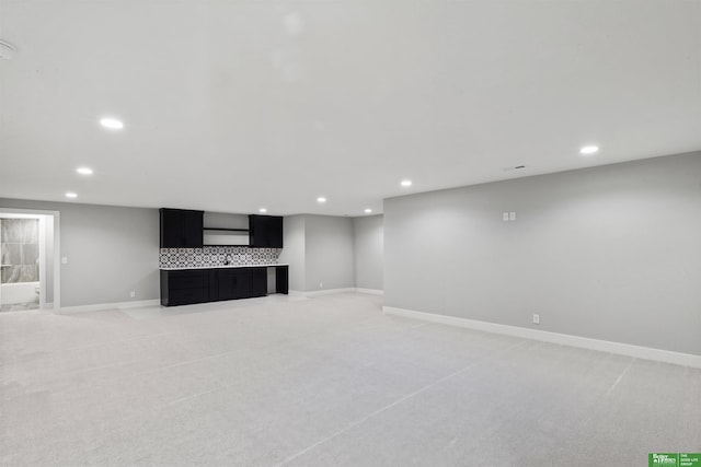 unfurnished living room with recessed lighting, light colored carpet, and baseboards