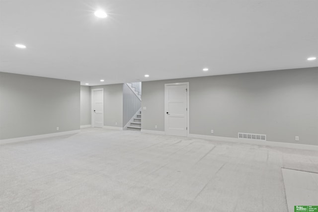 finished basement featuring light colored carpet, recessed lighting, visible vents, and stairway