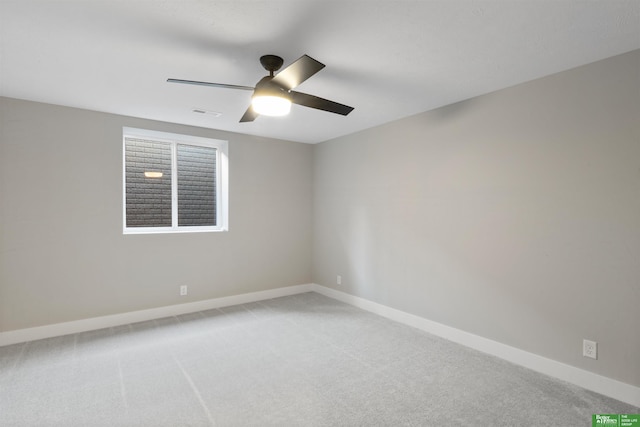 spare room featuring light carpet, ceiling fan, visible vents, and baseboards