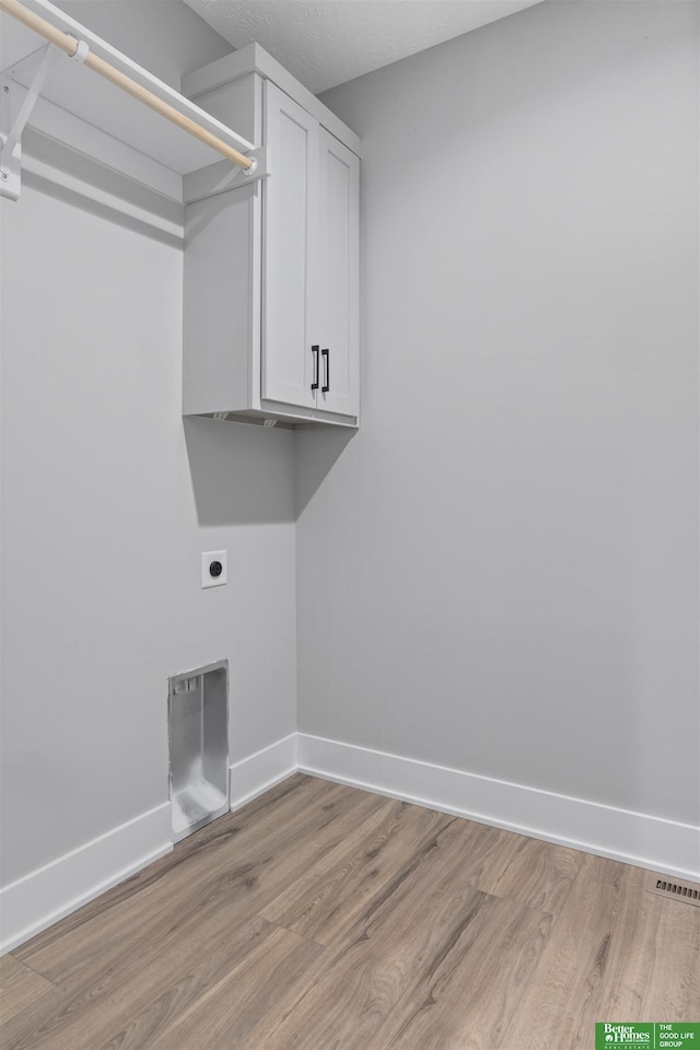 laundry room featuring cabinet space, baseboards, light wood-style floors, and hookup for an electric dryer