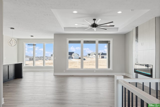 interior space featuring a raised ceiling, baseboards, and wood finished floors