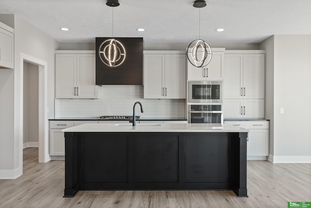 kitchen with a sink, stainless steel oven, wall chimney range hood, backsplash, and built in microwave