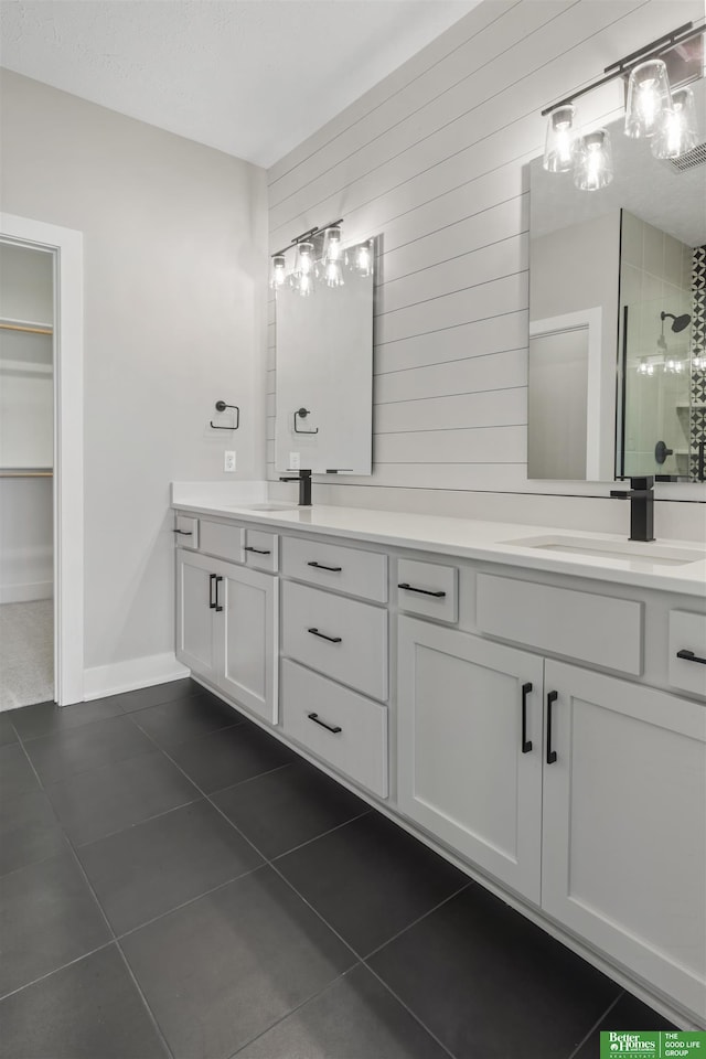 full bathroom with double vanity, a stall shower, a sink, and tile patterned floors