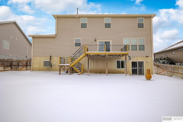 snow covered rear of property with cooling unit, a fenced backyard, a deck, and stairs