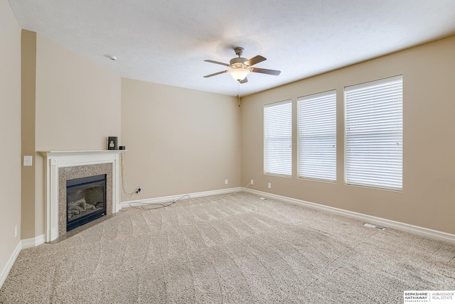 unfurnished living room with visible vents, baseboards, a ceiling fan, carpet, and a high end fireplace