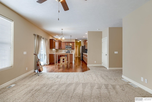 kitchen featuring a kitchen island, a kitchen breakfast bar, light countertops, appliances with stainless steel finishes, and hanging light fixtures