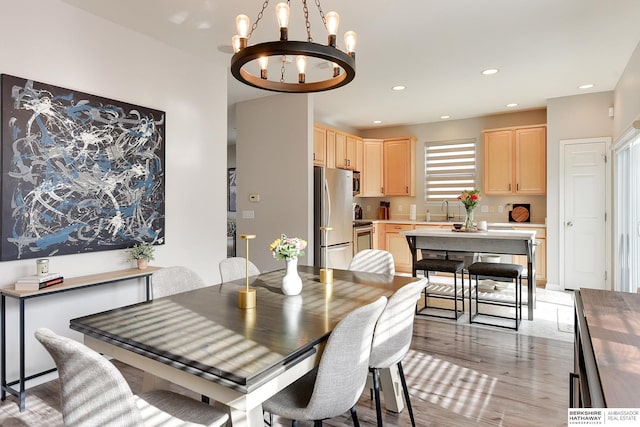 dining room with sink, a chandelier, and light wood-type flooring