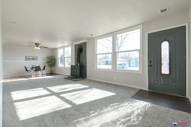 foyer entrance with dark colored carpet and a wood stove