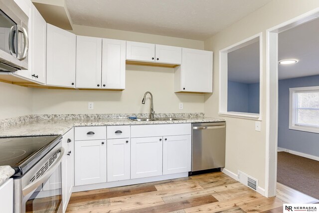 kitchen featuring white cabinetry, appliances with stainless steel finishes, sink, and light hardwood / wood-style floors