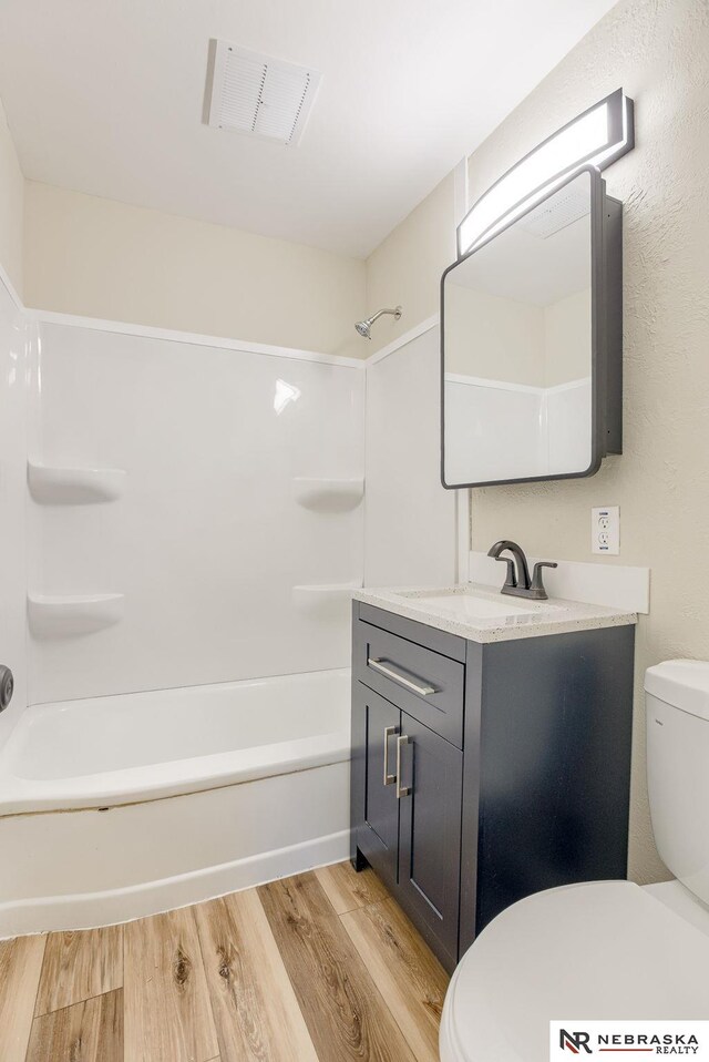 full bathroom featuring hardwood / wood-style flooring, shower / bath combination, vanity, and toilet