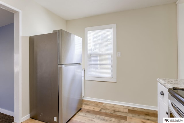 kitchen with white cabinetry, stainless steel fridge, and light hardwood / wood-style flooring