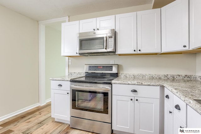 kitchen featuring light stone counters, light wood-type flooring, white cabinets, and appliances with stainless steel finishes