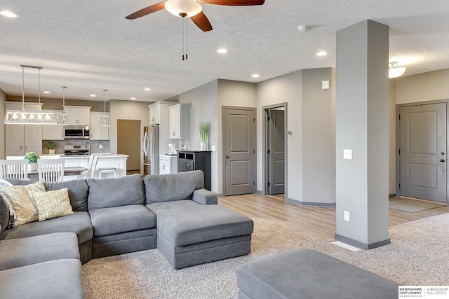 carpeted living room featuring ceiling fan and a textured ceiling