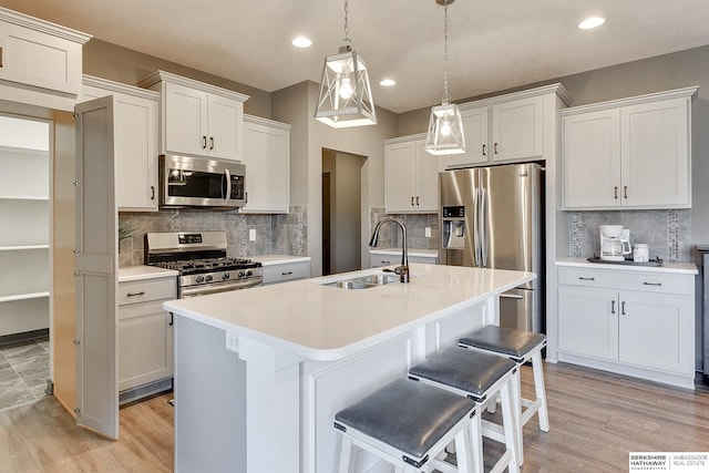 kitchen featuring appliances with stainless steel finishes, sink, a center island with sink, and white cabinets