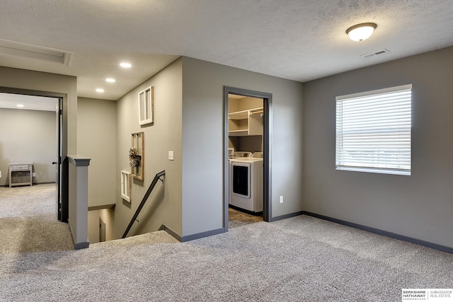 interior space with separate washer and dryer, a textured ceiling, and dark colored carpet